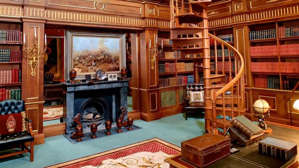  A grand library features a spiral staircase to an upper floor