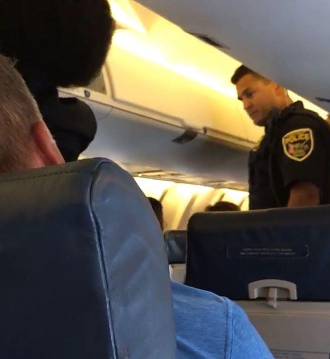  A police officer is seen entering the cabin before the eight people were thrown off the flight