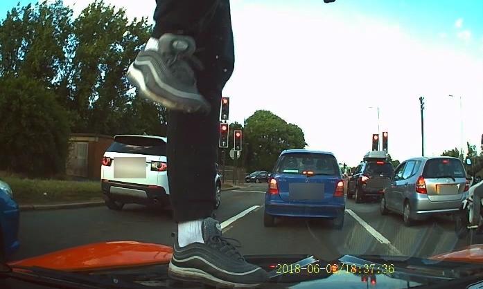 This moped mugger was filmed kicking a car windscreen in a daylight attack as his accomplices wielded a hammer and knife