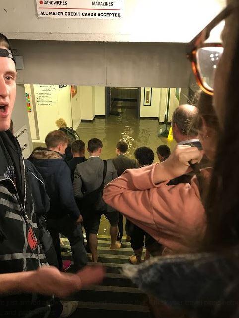  Commuters at Didcot train station pictured without shoes as they prepare to walk through floodwater