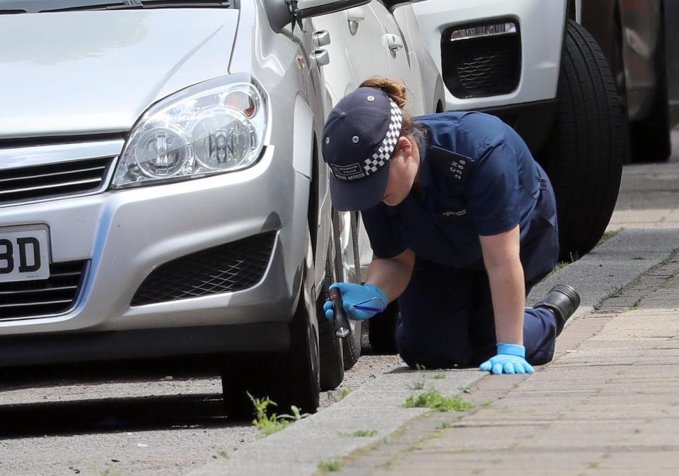  A police officer works her way along the street as she searches for evidence into the shooting of the young man