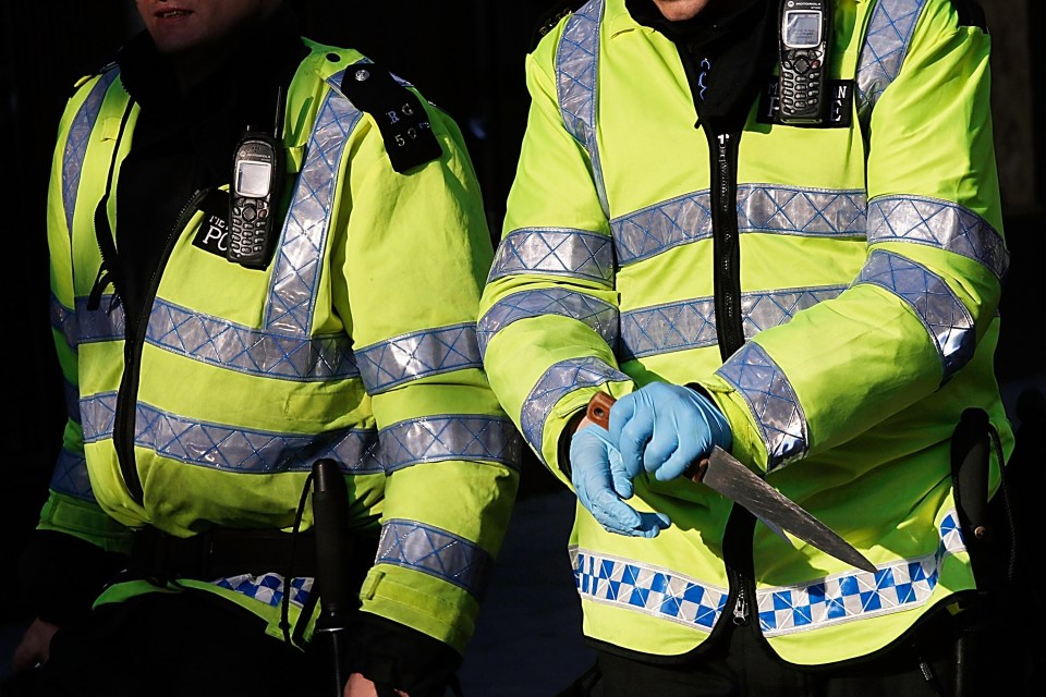 A police officer carefully handles a knife confiscated during the Notting Hill Carnival