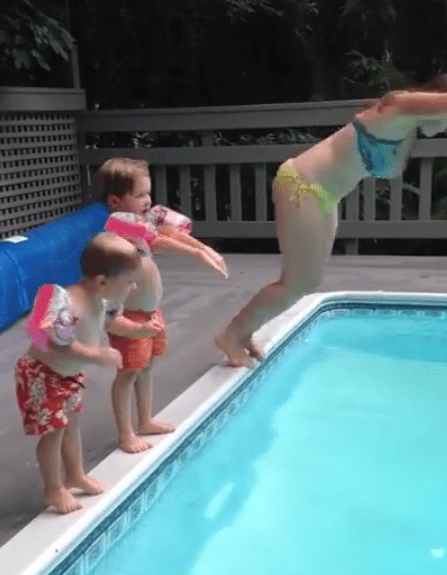  The two boys watch their mum dive off the edge of the swimming pool