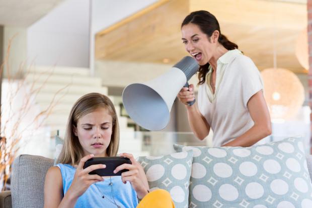 A child plays on a phone as her mum shouts