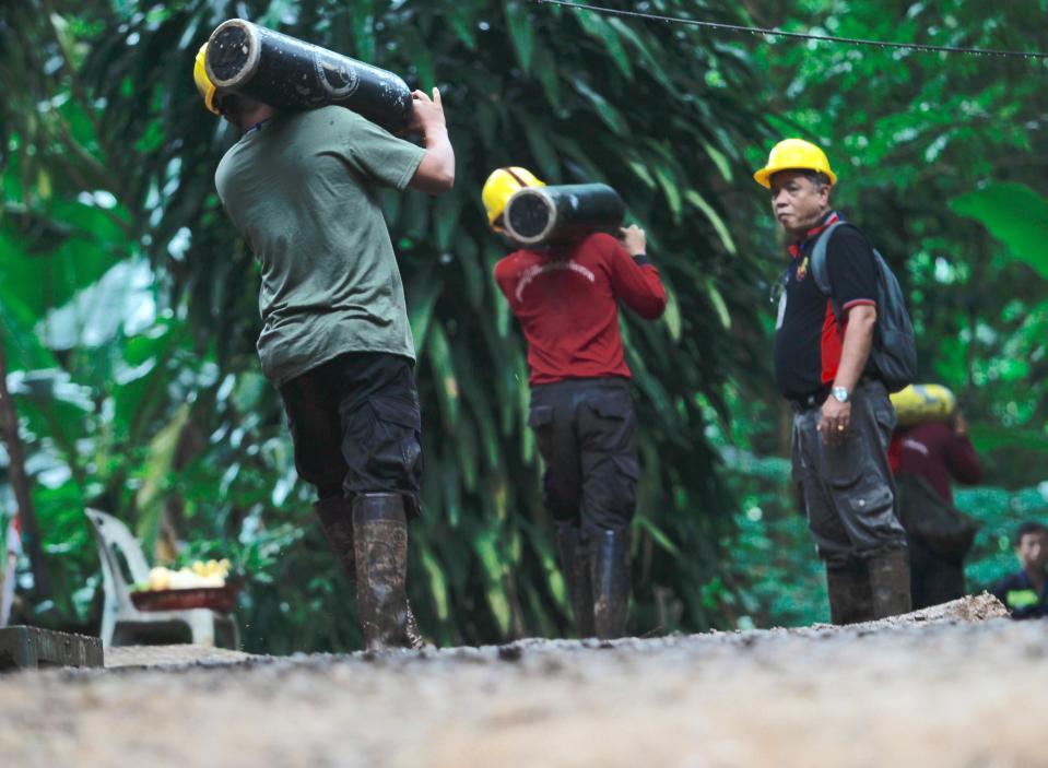  Rescuers haul equipment into the entrance of the cave