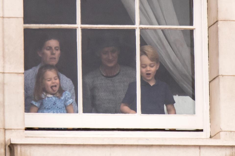  Cheeky Charlotte was caught sticking her tongue out as she peered through the window at Buckingham Palace