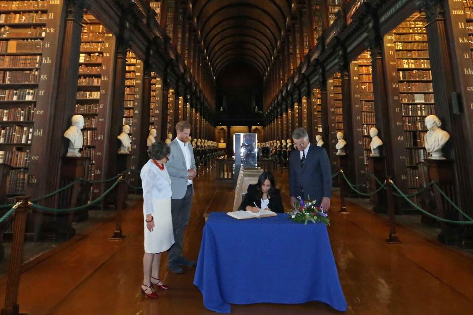  The Duke and Duchess of Sussex sign the visitors book, watched by Trinity, Provost and President