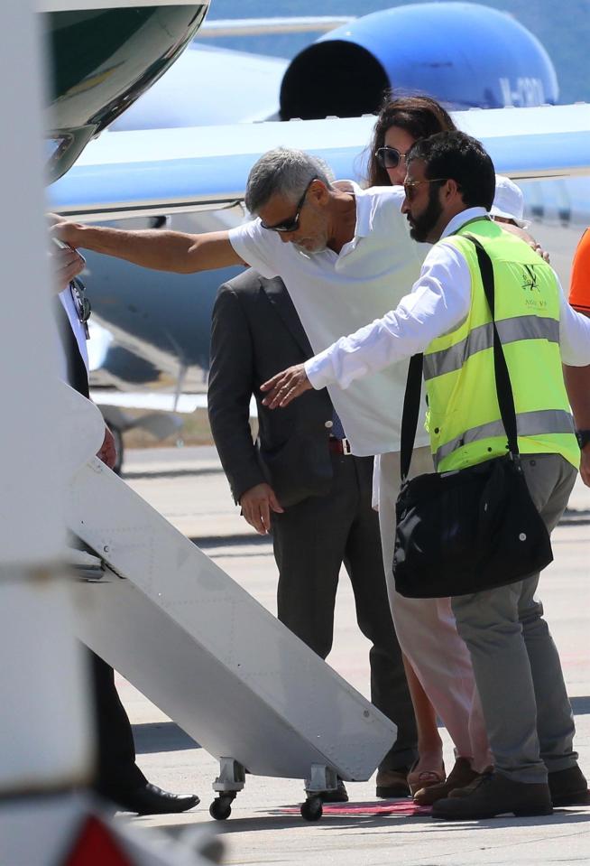  Amal and a security official helped Clooney as he walked a little gingerly into his private jet