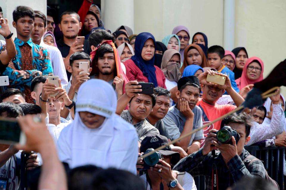  The crowd film as a woman is being beaten