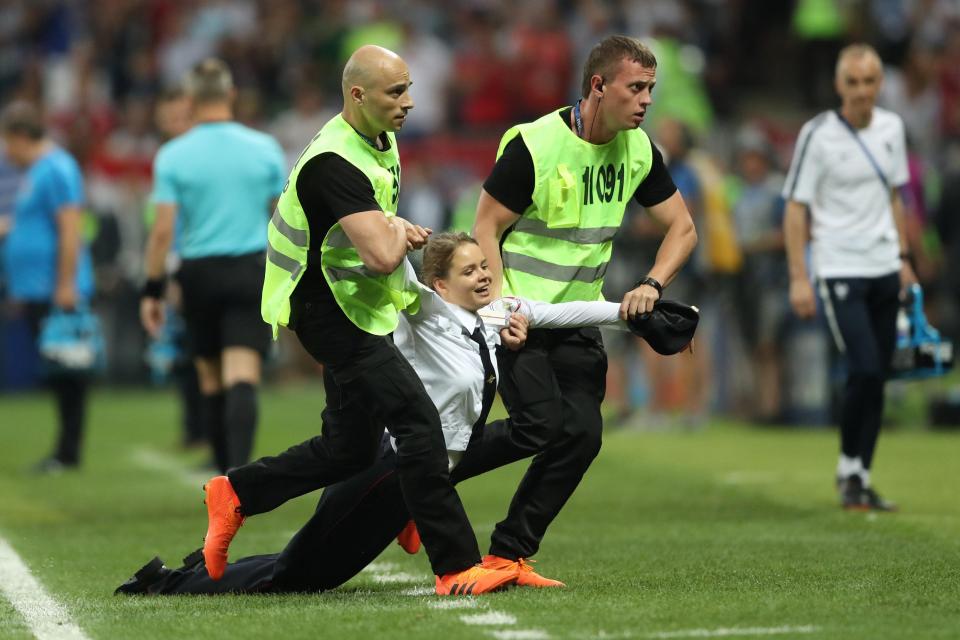  Security drags away a pitch invader after she made her way on the pitch at the Luzhniki Stadium