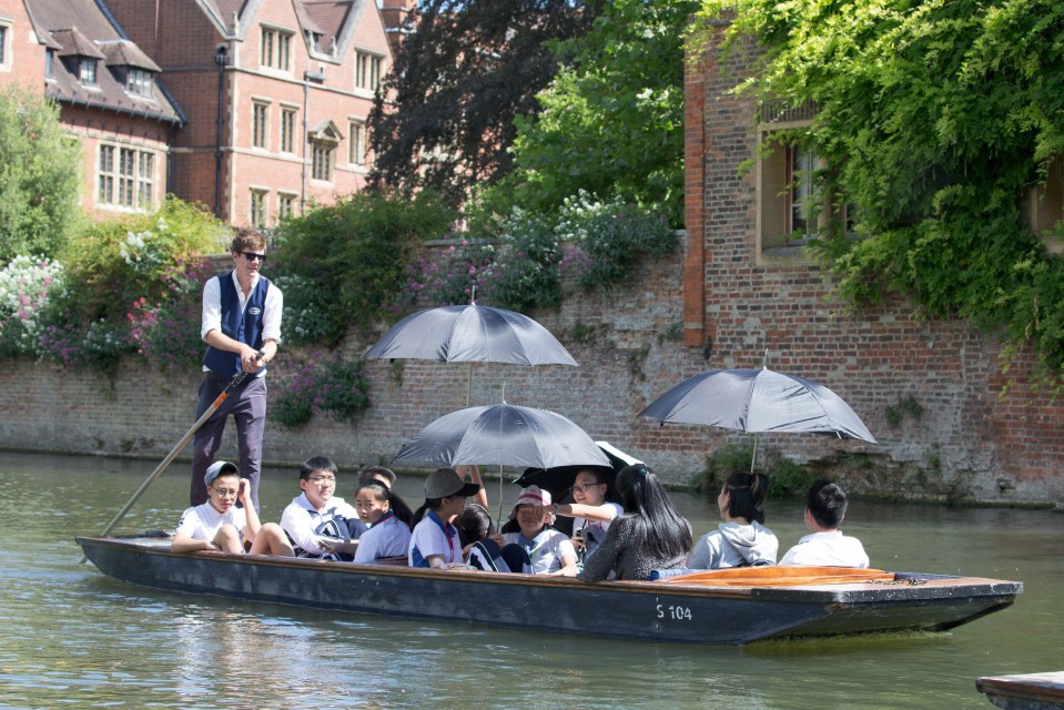 Tourists using umbrellas to try and stay cool whilst out punting on the River Cam