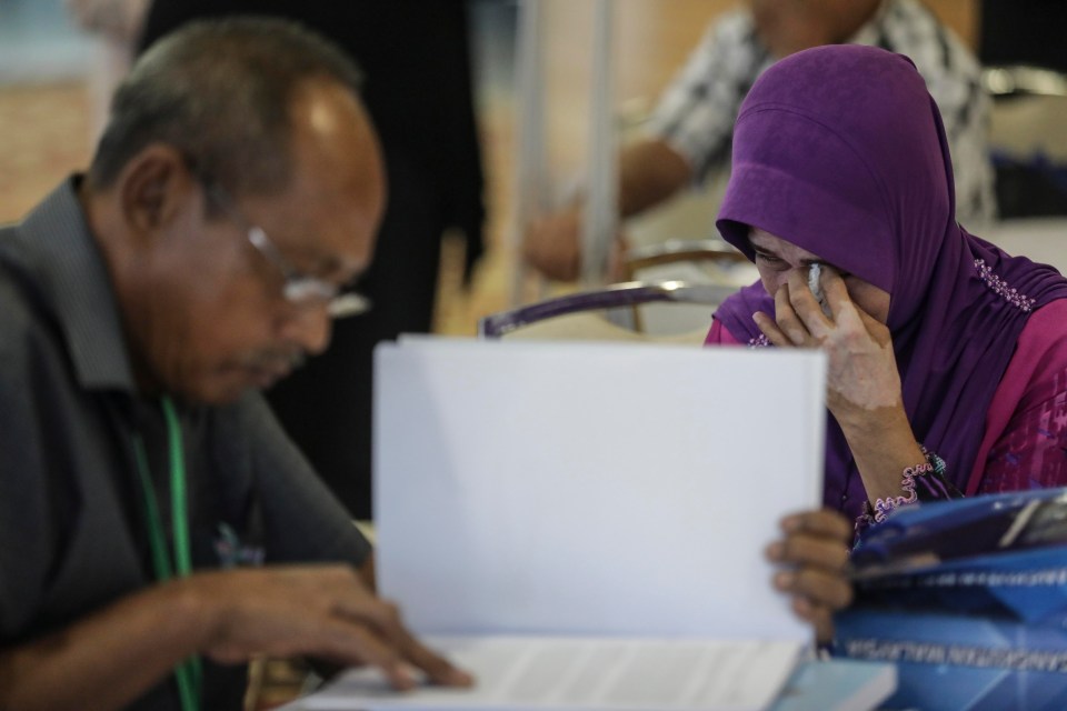 Relatives of the passengers of the doomed MH370 flight weep as they read the report into the disaster