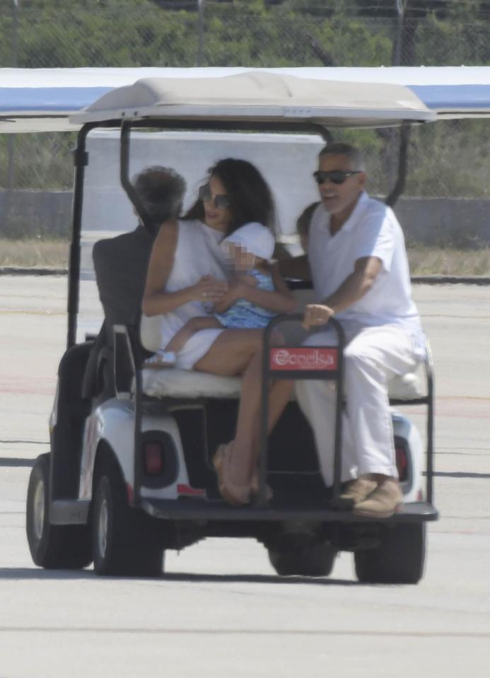  Clooney arrived at the tarmac in Olbia, north-east Sardinia, with wife Amal and daughter Ella