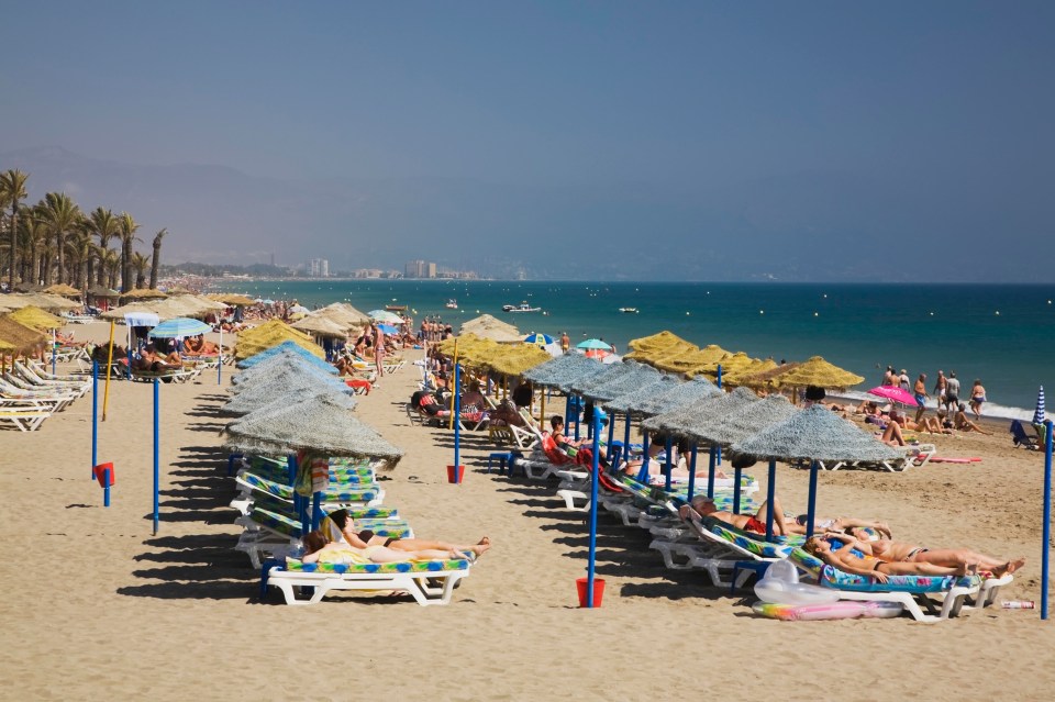 Sunbathers enjoying the beach in Torremolinos, Costa del Sol, Spain