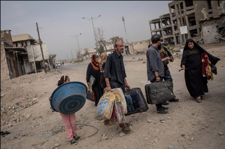  Civilians carry their belongings on a destroyed street in West Mosul