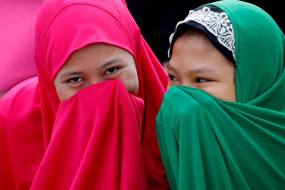 Filipino Muslims cover their faces as they gather outside the Blue Mosque to pray