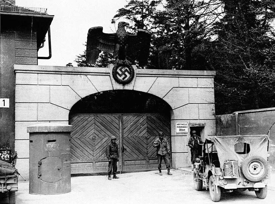 Soldiers stand in front of the gate of Dachau Concentration Camp, in Dachau, Germany