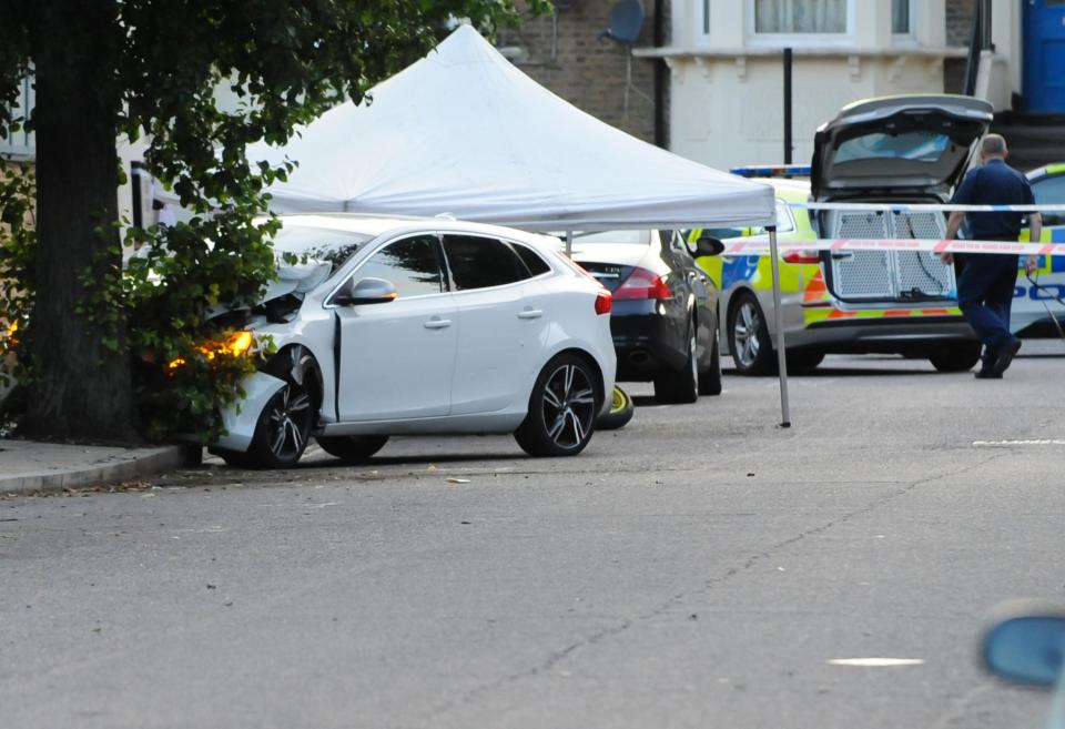  A crashed white car is cordoned off by cops investigating the shooting