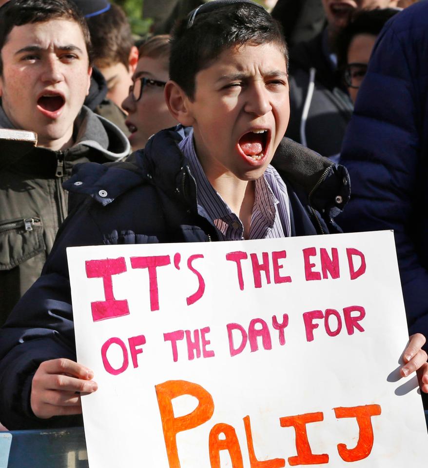  A student from the Orthodox Jewish Rambam Mesivta high school holds a sign as he and schoolmates protest across the street from the house of Palij