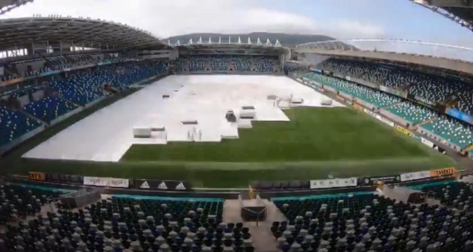  Slowly the pitch is covered with white plastic as the stage gets set for a boxing bumper bill