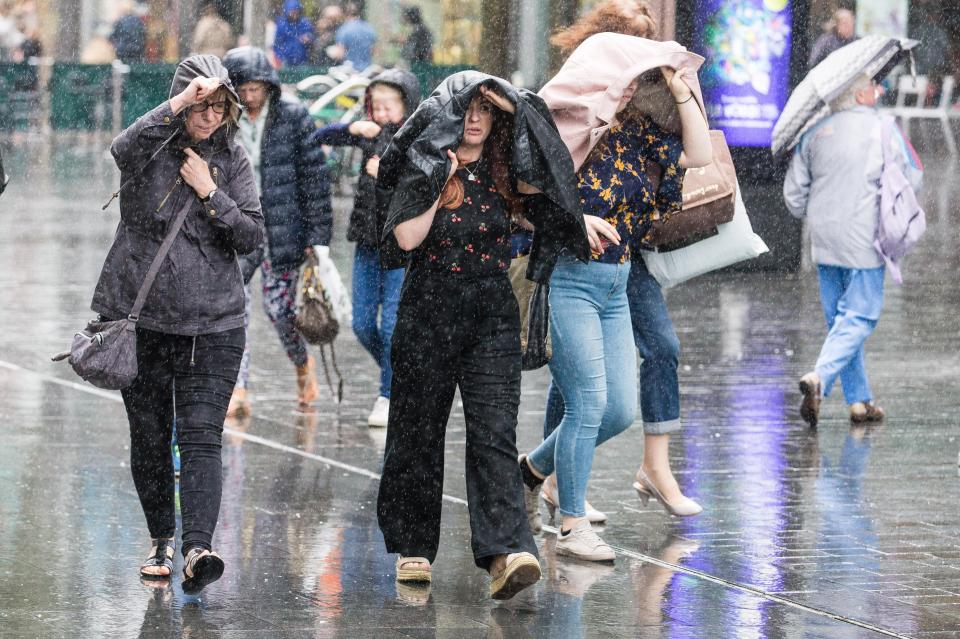  Shoppers shelter from heavy rain in Liverpool city centre as warm weather turns to wind and rain