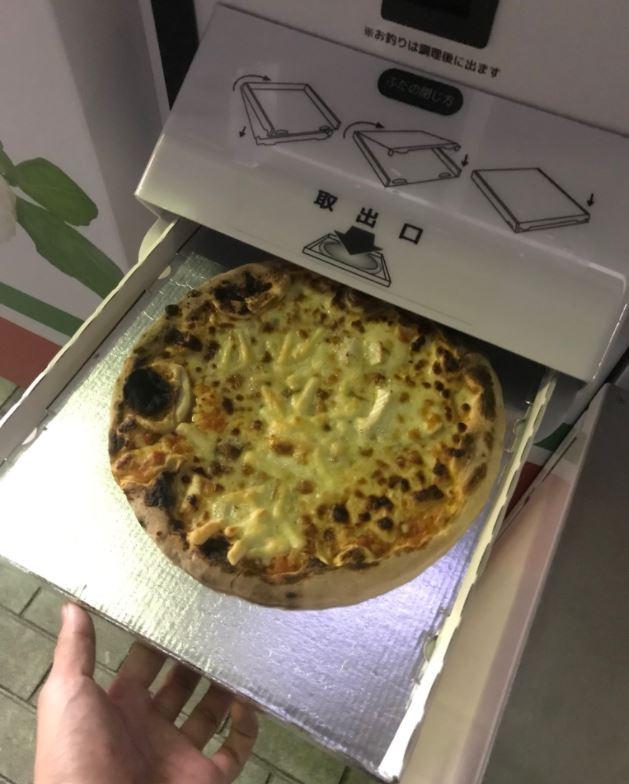  The pizza is dispensed in a takeaway-style box