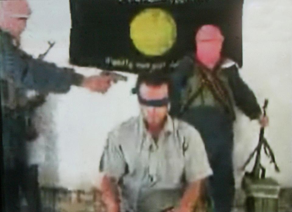  An image grab from 2004 on the website affiliated to Al-Qaeda shows a masked man pointing his gun towards a blindfolded Turkish hostage