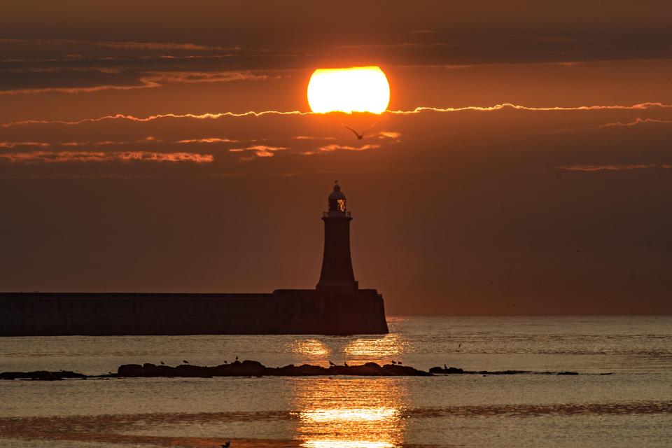  The sun rises above the lighthouse at the mouth of the River Tyne this morning