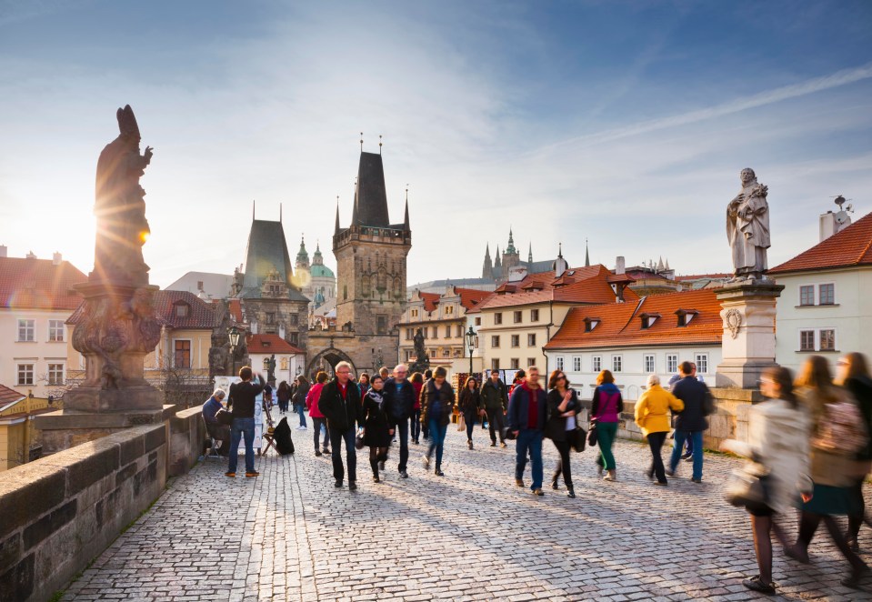 People strolling on the Charles Bridge at sunset in Prague.