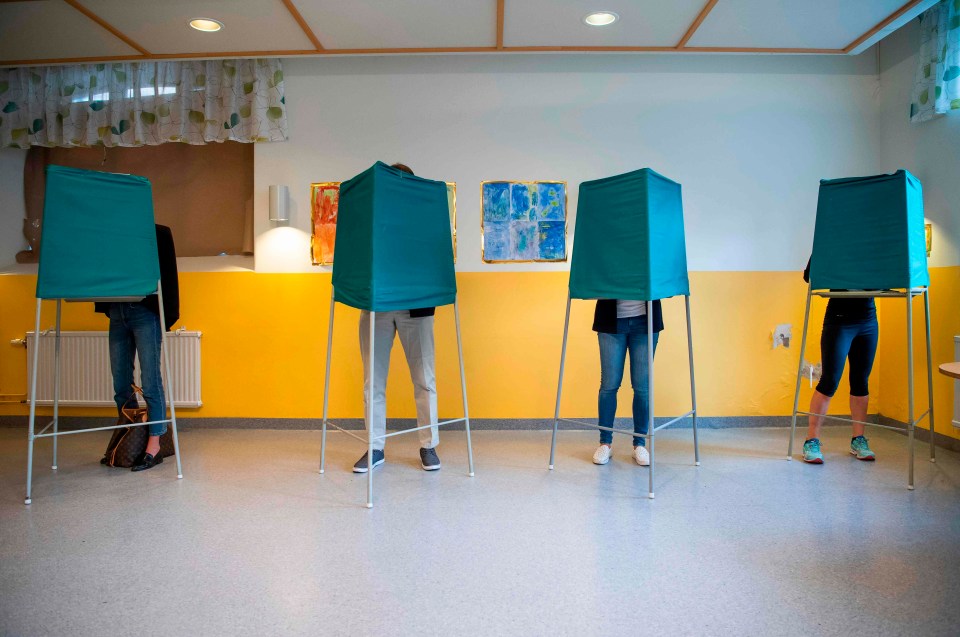 People stand on booths at a polling station during the Swedish general elections in Stockholm 