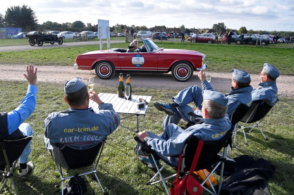  Visitors wave to a couple in their vehicle as they cruise past the mechanics