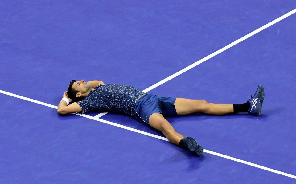 Novak Djokovic lays on the ground in triumph after winning the US Open