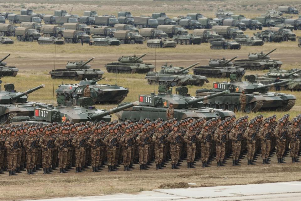  Chinese servicemen stand with their arms in front of the country's military hardware