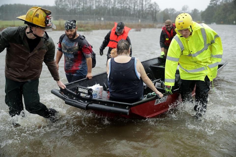  Rescue workers save a woman and her dog from their flooded home in James City