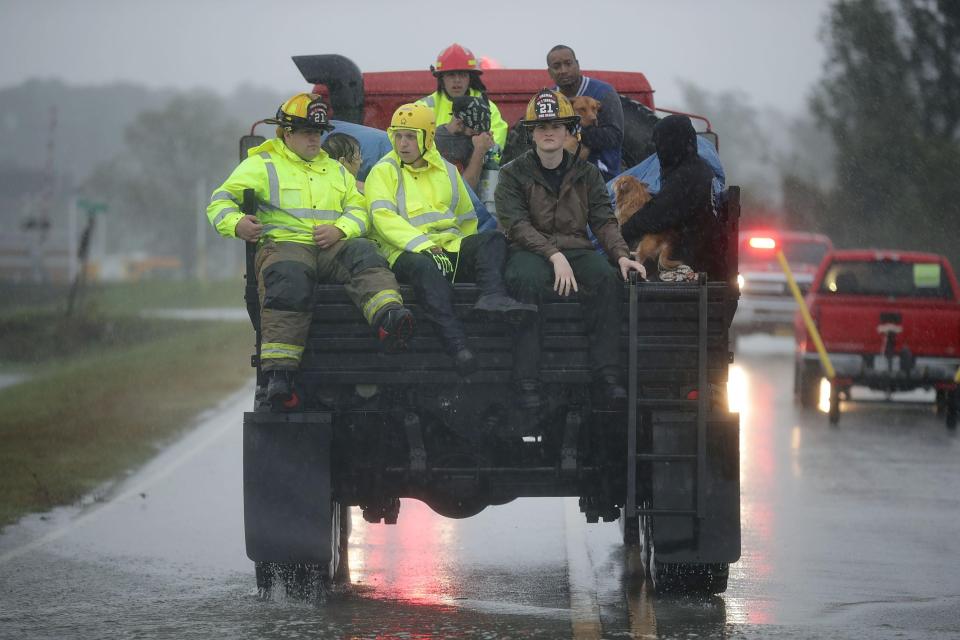  Rescue workers use a truck to move people rescued from their flooded homes