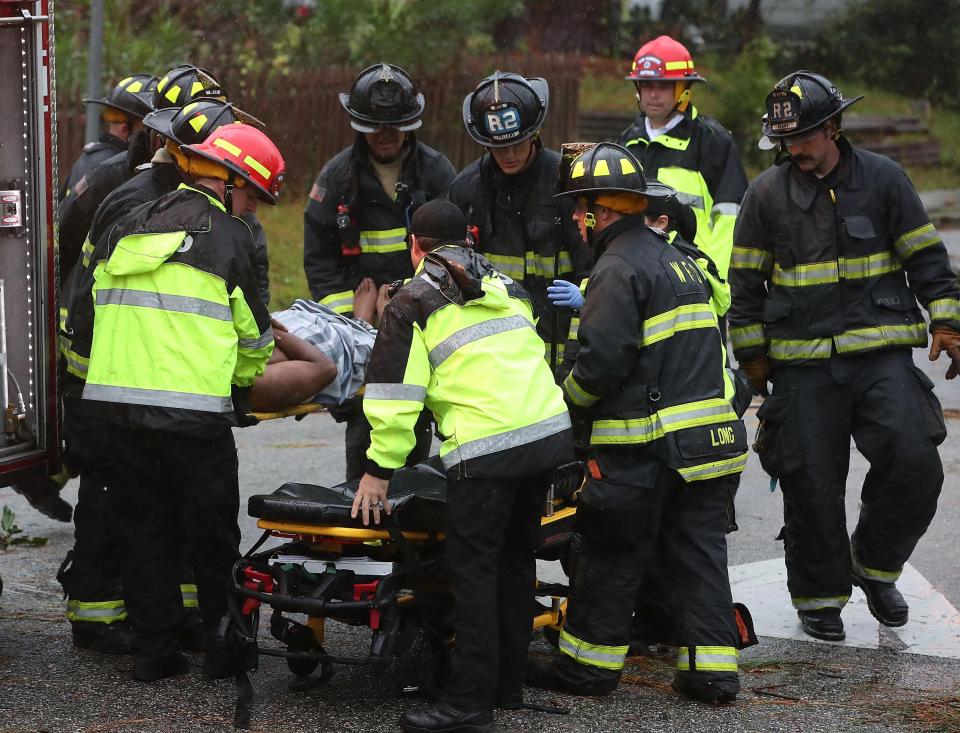  Rescue workers pull a man from a house after a tree toppled onto it, killing two other people