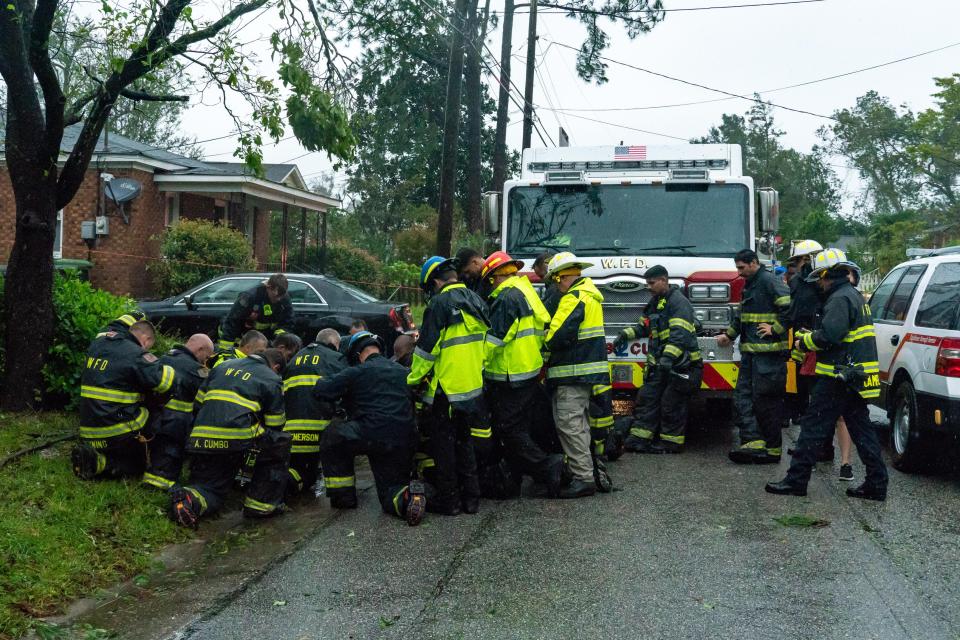  Rescue workers, police and fire department members wait to remove the bodies of a mother and child who were killed by a falling tree in Wilmington, NC