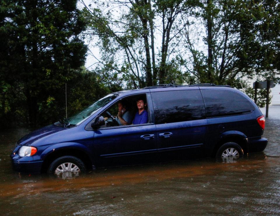  A family is stalled in water as they wait to be rescued