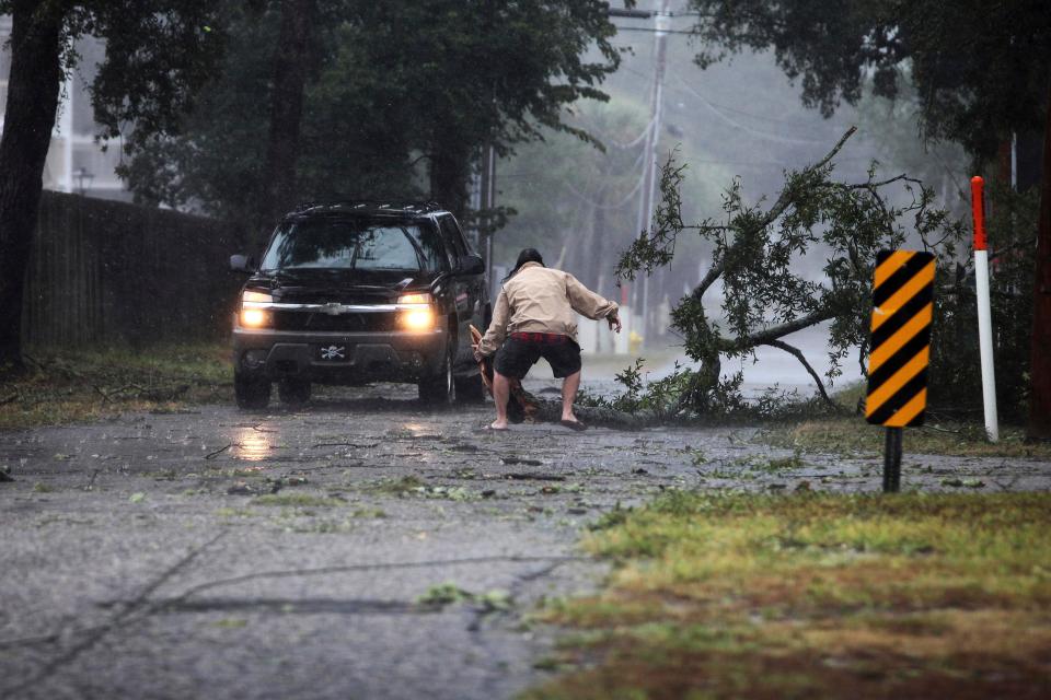  A man moves a large tree limb that downed power lines as the hurricane-turned-tropical storm Florence hit the Cherry Grove community in North Myrtle Beach, South Carolina