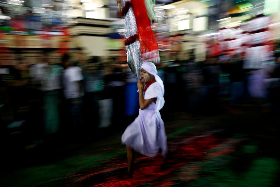 A young Myanmar Shiite Muslim boy runs over a burning coal fire