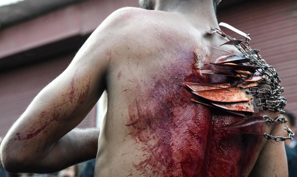 This Shia muslim begins to use the chained up blades as he parades through the streets in Kashmire, Paskinstan