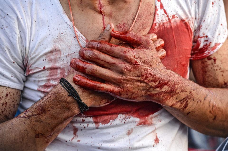 A worshipper clutches his blood soaked chest after a bout of self-flagellation