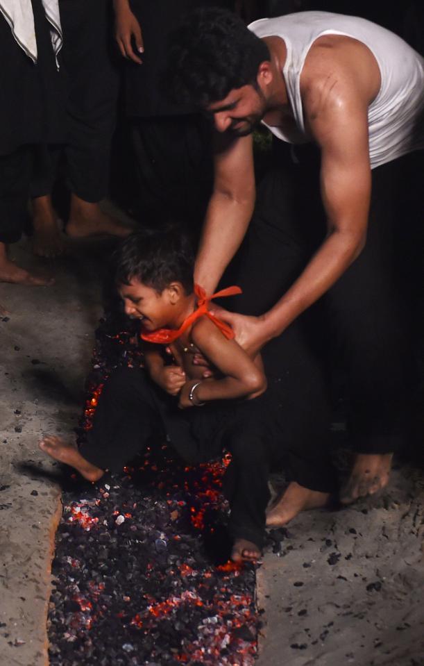 A Pakistani Shiite Muslim man stands his son over burning coal during a commemoration of the martyrdom