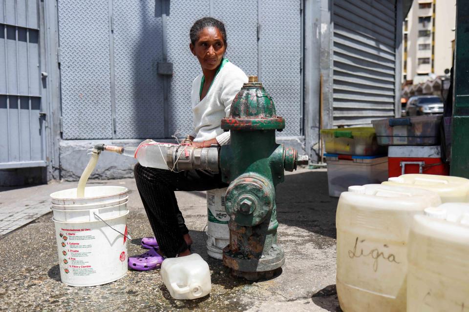  Maribel Gonzales struggles to extract trickling water from a standpipe as her children cry from thirst