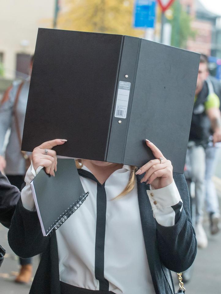  Harris hides her face behind a folder as she leaves the court