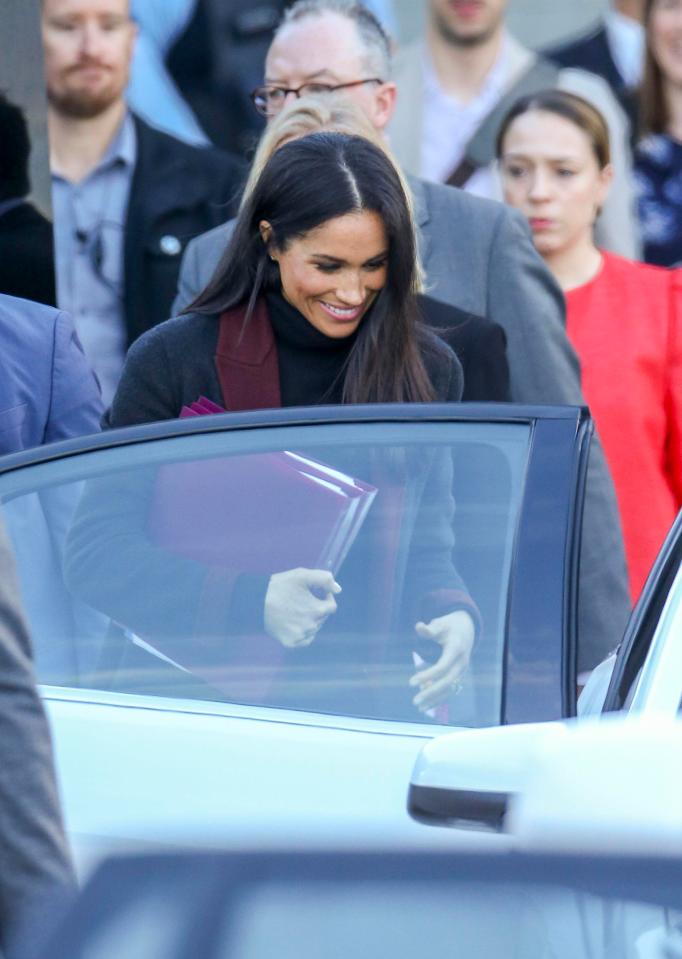  Meghan held two purple folders as she was ushered into the car