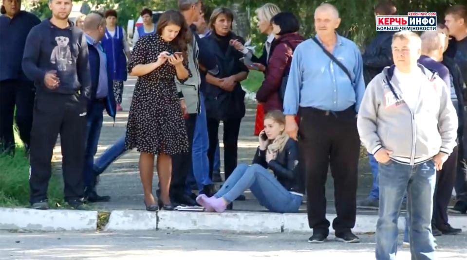  Frightened students make phone calls from outside the college where a bomb had detonated