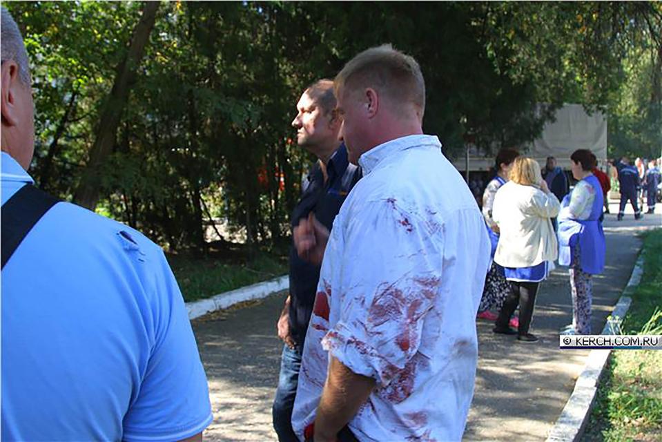  A man in a blood-stained shirt outside the college where the bomb detonated