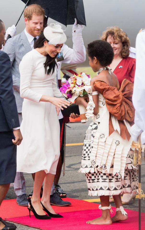  One of the welcome party in traditional dress gives Meghan a bunch of flowers