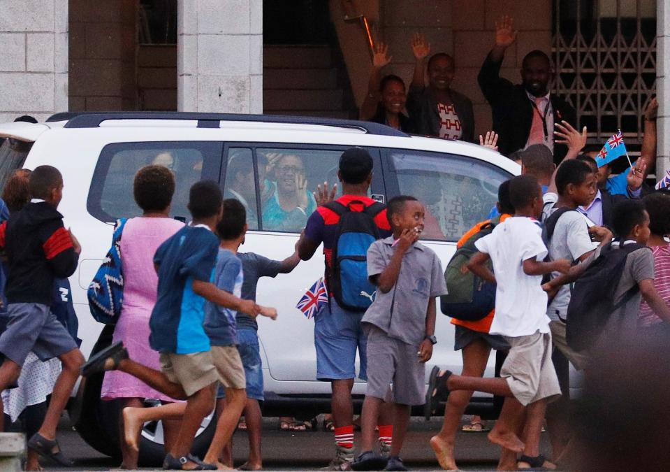  Excited kids run alongside the car carrying the royal couple as Harry waves